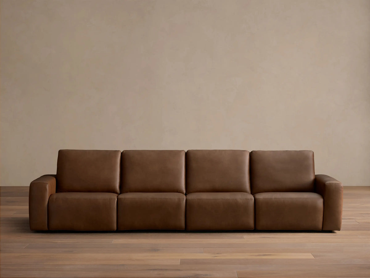 Front view of the brown Brennan Leather Four-Piece Motion Sectional with four plush sections.