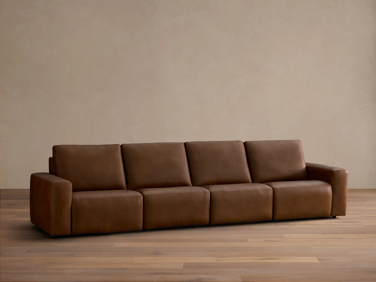 Front view of the brown Brennan Leather Four-Piece Motion Sectional with four plush sections.