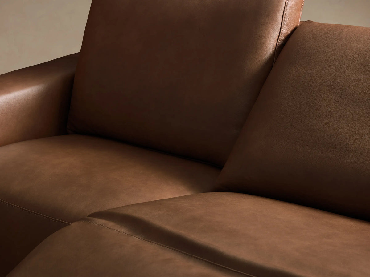 Front view of the brown Brennan Leather Four-Piece Motion Sectional, a sleek, modern sofa with four distinct seat sections.