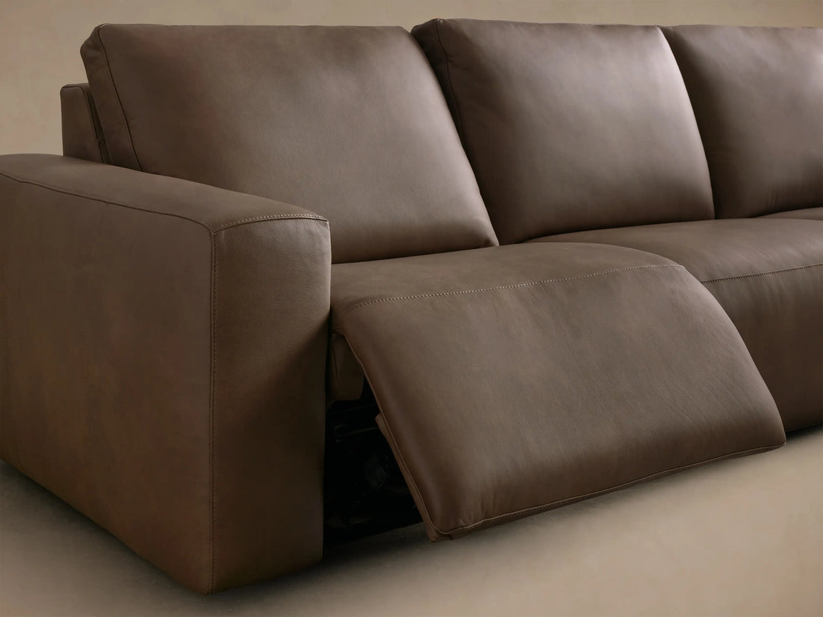 Close-up of brown leather upholstery with two black motion control buttons on the Brennan Leather Four-Piece Motion Sectional.