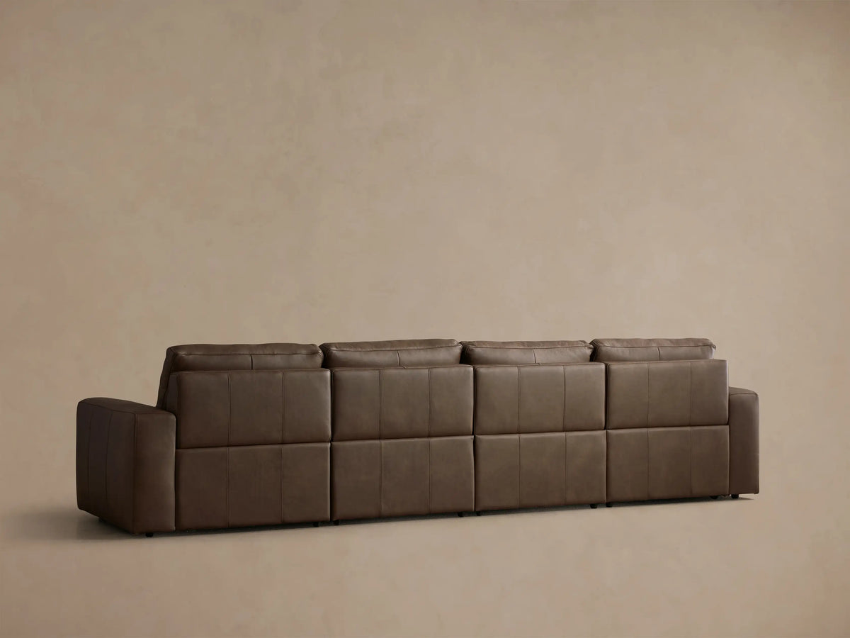Close-up of the brown Brennan Leather Four-Piece Motion Sectional, showing the left arm and a footrest extended on one recliner unit.