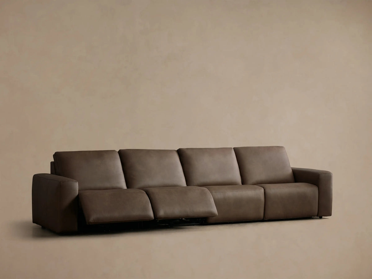 Front view of the brown Brennan Leather Four-Piece Motion Sectional, with the two rightmost seats reclined and footrests extended.