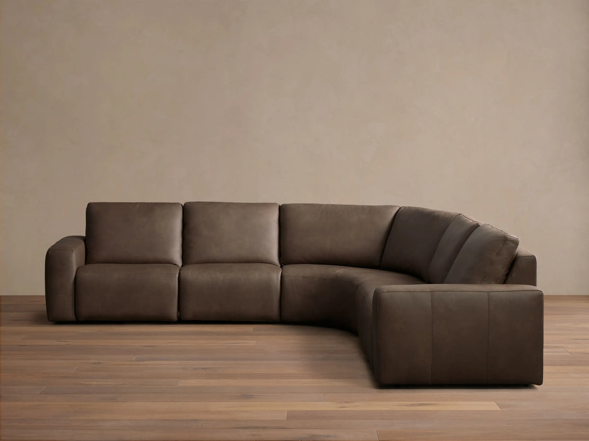 Front view of the brown Brennan Leather Five-Piece Motion Corner Sectional, an L-shaped sofa with smooth cushions.