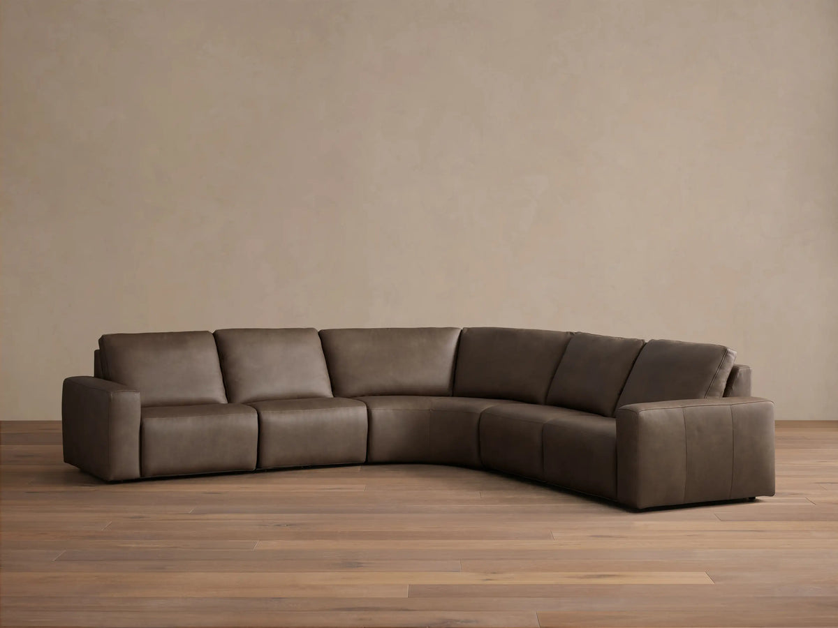 Front view of the brown Brennan Leather Five-Piece Motion Corner Sectional, an L-shaped sofa with smooth cushions.