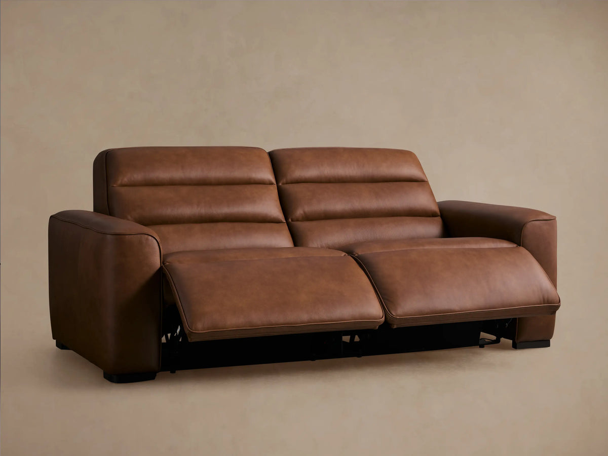 Warm brown Borough Leather Two-Piece Motion Sofa, both recliners extended, showing footrests, angled against a beige wall.