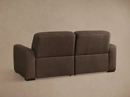 Angled view of a brown leather Borough Two-Piece Motion Sofa; the right seat is reclined with its footrest extended.