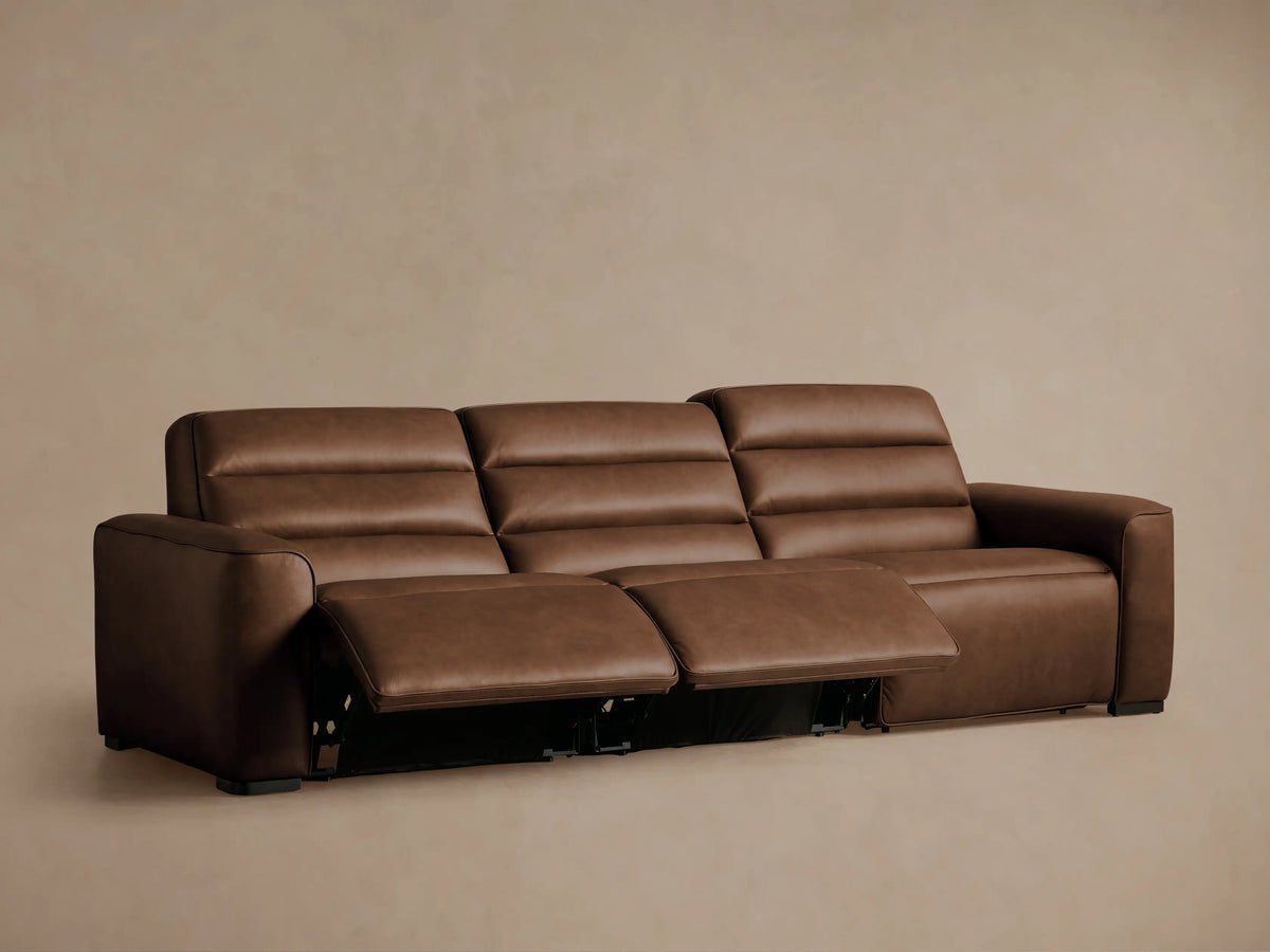 Close-up of a brown leather Borough Motion Sofa, showing neat stitching and two embedded oval-shaped control buttons.