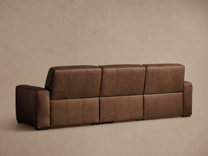Brown leather 3-piece Borough Motion Sofa, right seat reclined with footrest extended, against a light brown wall.