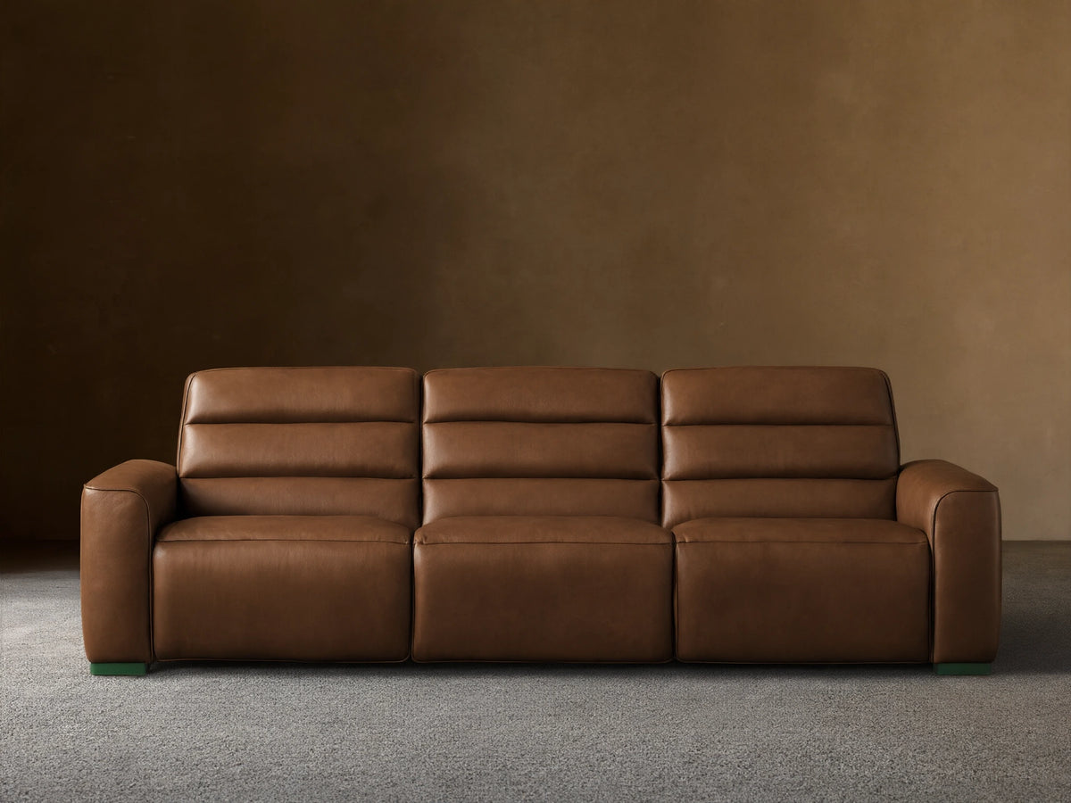 Front view of Borough Three-Piece Motion Sofa in rich brown leather, featuring plush, segmented cushions, on a wood floor.