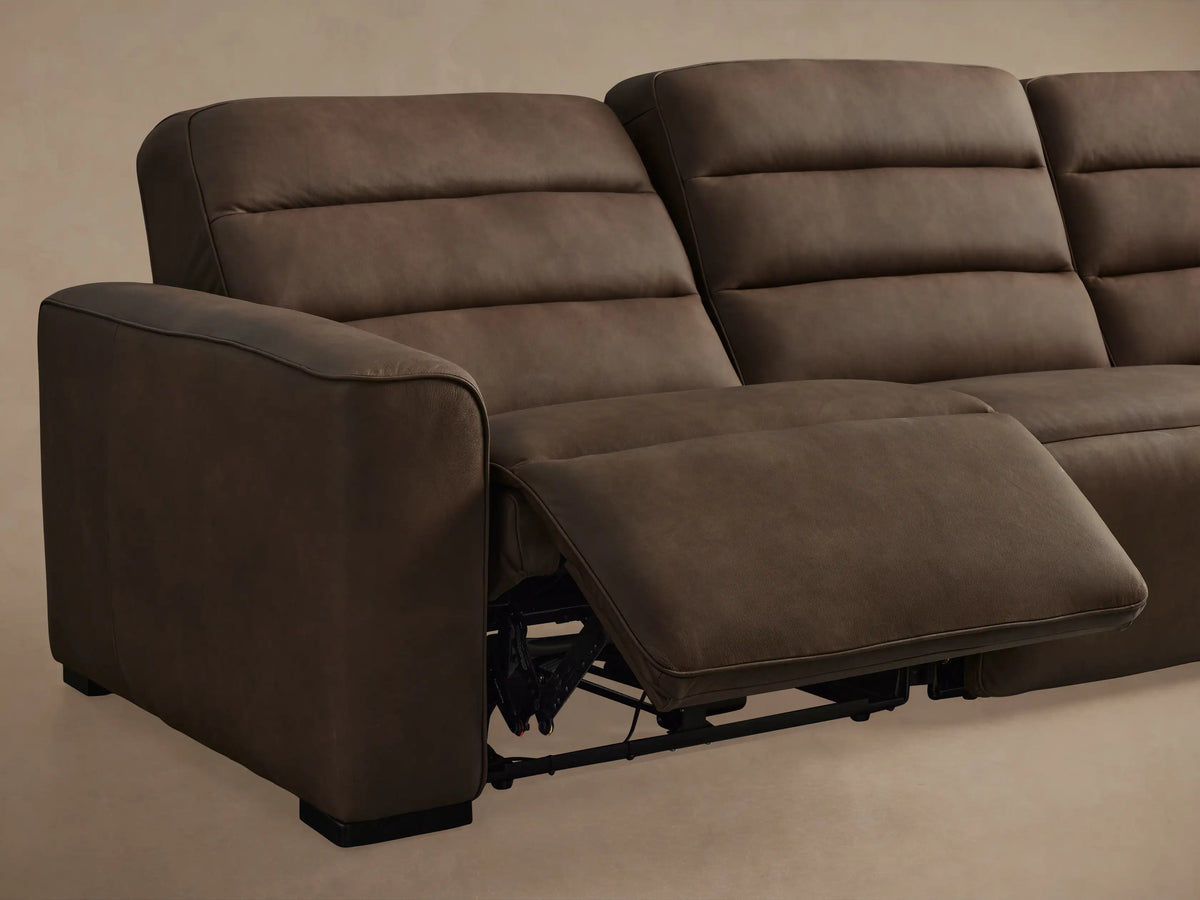 Close-up of a Borough Leather Three-Piece Motion Sofa, revealing brown textured leather and two black oval motion control buttons.