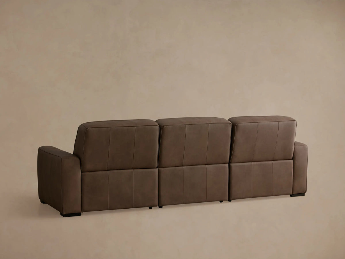 Angled view of a brown leather Borough Three-Piece Motion Sofa, left recliner with its footrest extended.