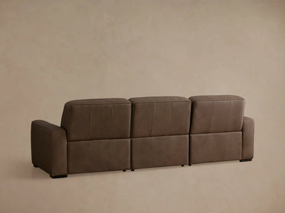 Angled view of a brown leather Borough Three-Piece Motion Sofa, left recliner with its footrest extended.