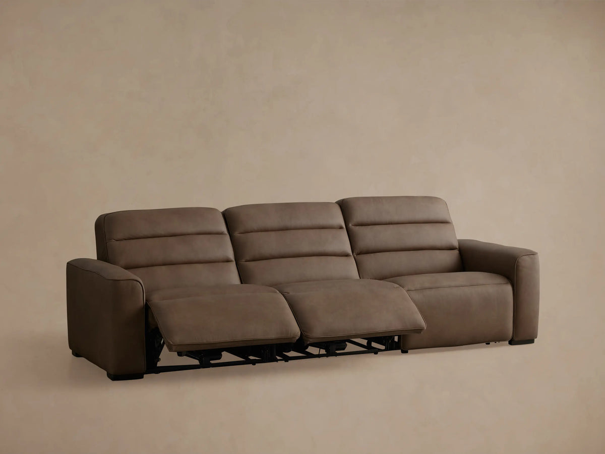 Borough Leather Three-Piece Motion Sofa in brown; right section reclined with footrest extended against a beige wall.