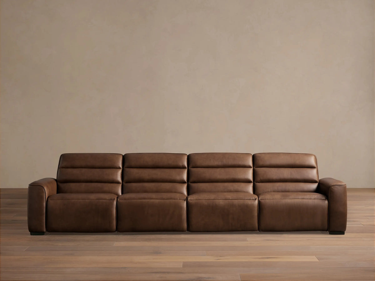 Borough Leather Four-Piece Motion Sectional, front view, rich brown leather, against a light beige wall on a wood floor.