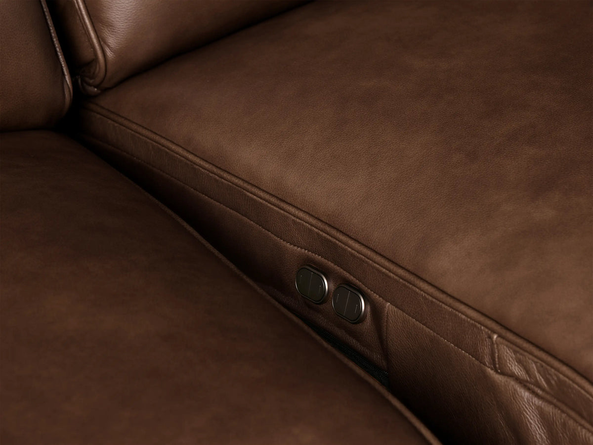 Close-up of the Borough Leather Motion Sectional, showing rich brown leather armrest, cushion, and backrest with fine stitching.