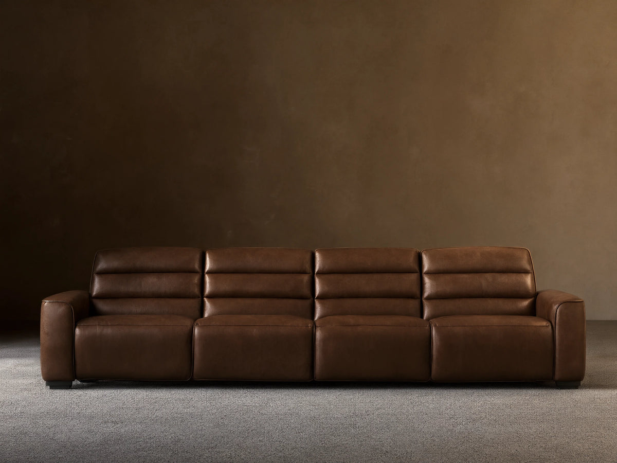 Borough Leather Four-Piece Motion Sectional, front view, rich brown leather, against a light beige wall on a wood floor.