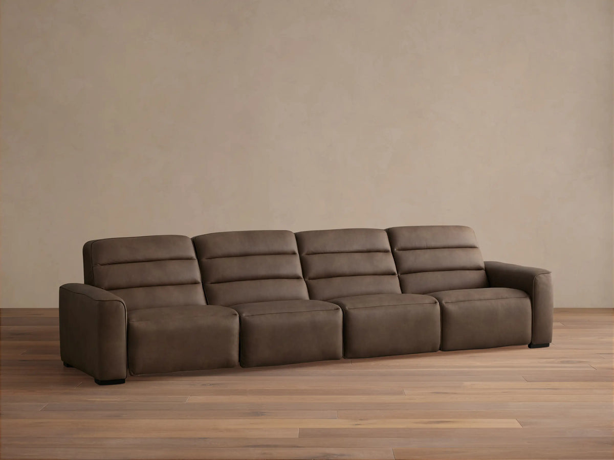 Borough Leather Four-Piece Motion Sectional in rich brown, with horizontal tufted backrests, on a wood floor against a light wall.
