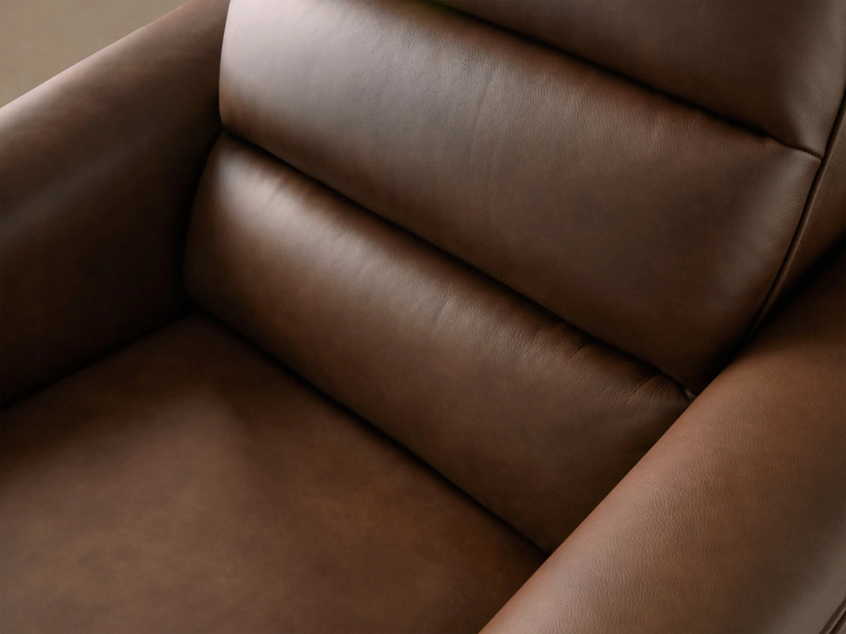 Warm brown leather Borough Motion Recliner with a padded backrest and sleek armrests, on a wooden floor.