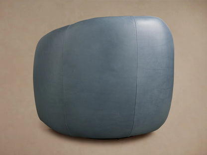 A side view of the Fresno Leather Swivel Chair in light blue leather, highlighting its smooth, curved backrest against a beige background.