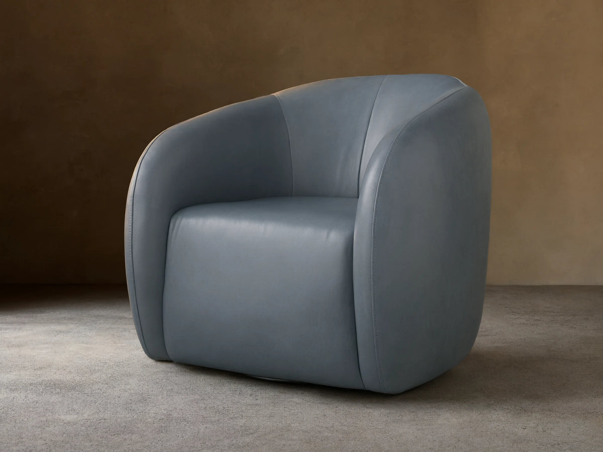 Fresno Leather Swivel Chair in blue-gray leather, featuring a curved, padded backrest and seat on a wooden floor, facing slightly left.