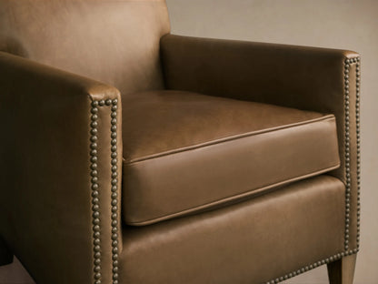 Close-up of the brown leather Kinsman Leather Chair, showing the seat cushion, armrest, and natural-finished nailhead trim.