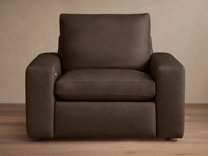 Wide arm leather motion recliner in dark brown leather, with plush seat and back cushions, on a wooden floor background.