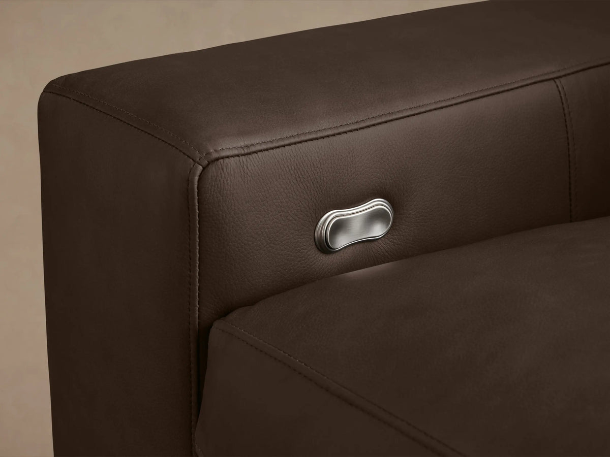 Kipton Wide Arm Leather Motion Recliner in dark brown leather, front-facing. Shows wide arms, cushioned seat, and backrest on wood floor.