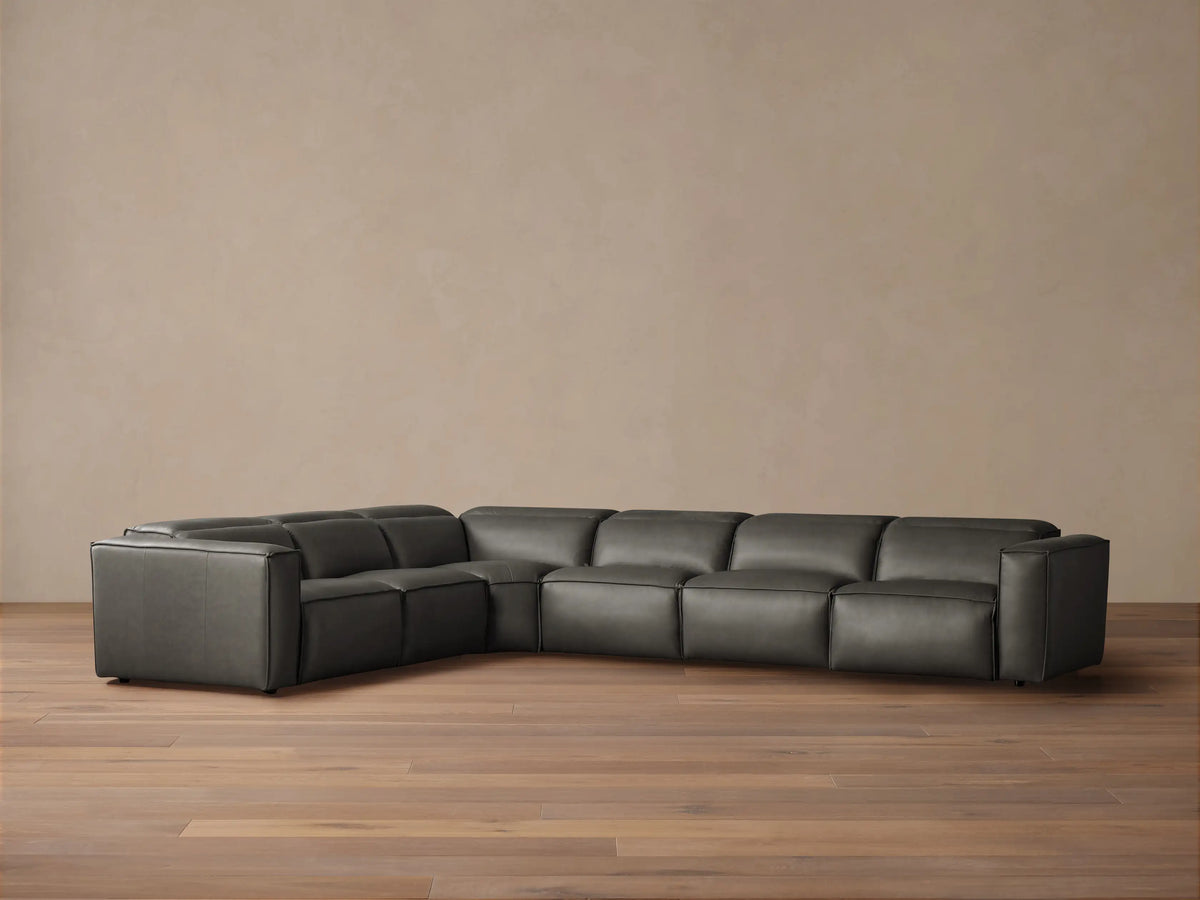 Dark gray leather Coburn Six Piece Motion Sectional, L-shaped, on a wood floor against a neutral wall.