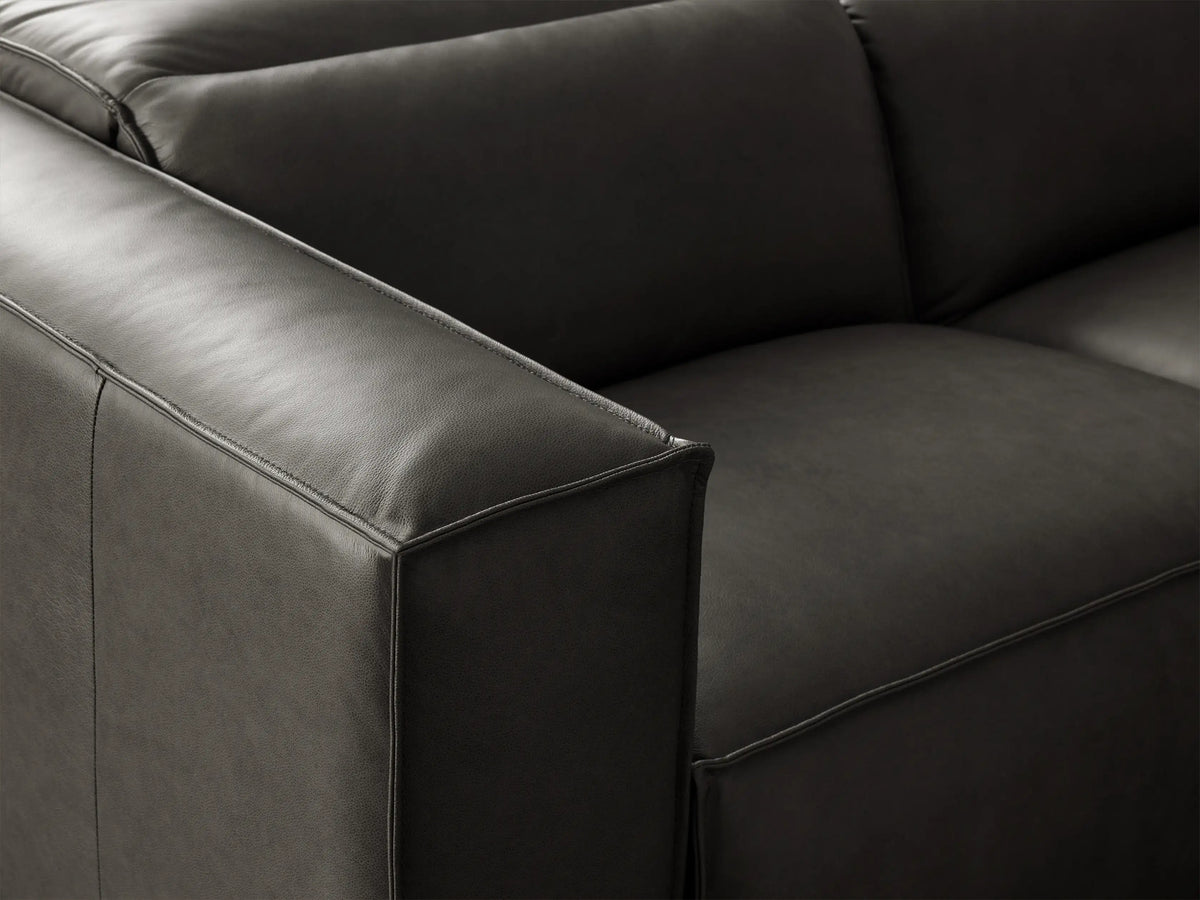 Charcoal leather Coburn Six Piece Motion Sectional in an L-shape on a wooden floor against a beige wall.