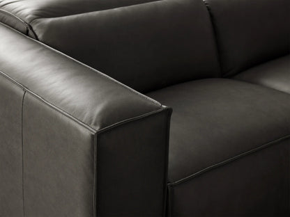 Charcoal leather Coburn Six Piece Motion Sectional in an L-shape on a wooden floor against a beige wall.