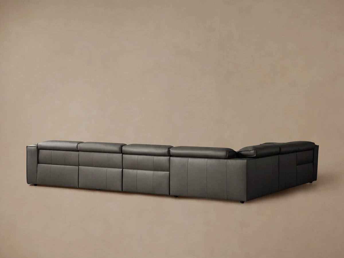 Dark grey Coburn Leather Sectional close-up showing armrest, seat, and back cushions with detailed stitching.