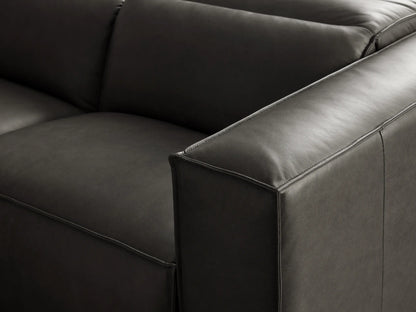 Dark gray leather L-shaped Coburn Six Piece Motion Sectional, viewed from front-right, on a gray floor in a minimalist setting.