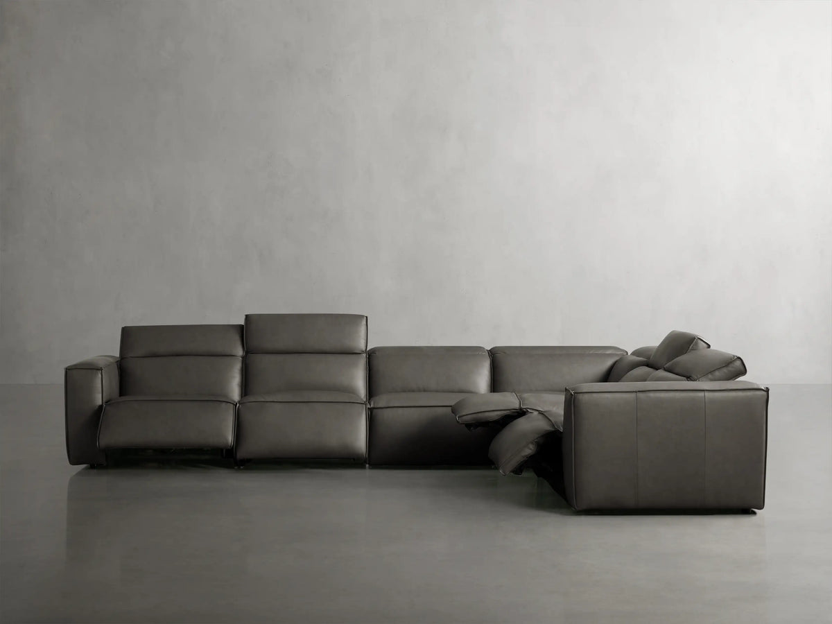 Close-up of Coburn Leather Six Piece Motion Sectional's dark gray leather armrest and cushions, highlighting fine stitching.