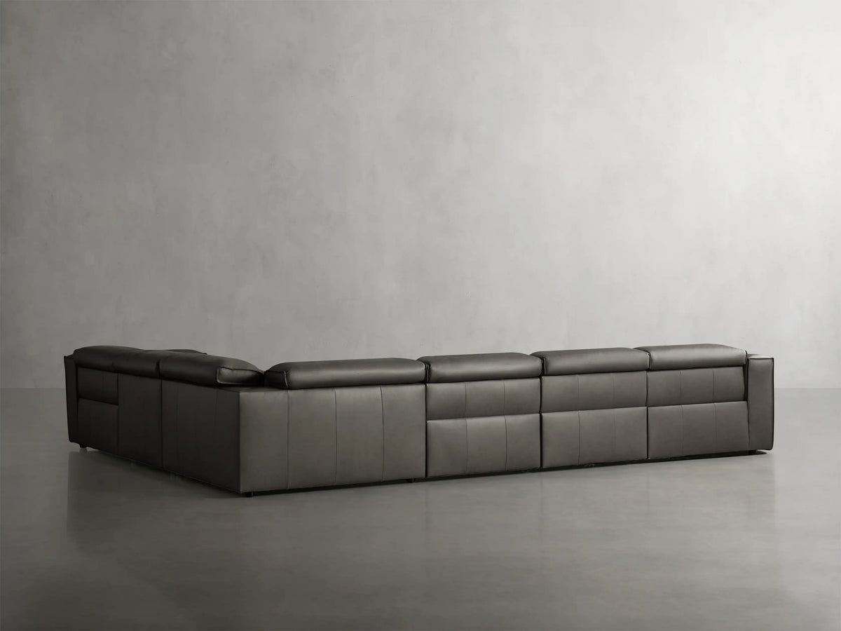 Dark gray leather Coburn 6-piece motion sectional sofa in L-shape; left and corner recliners extended, against a gray wall.