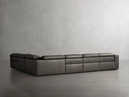 Dark gray leather Coburn 6-piece motion sectional sofa in L-shape; left and corner recliners extended, against a gray wall.