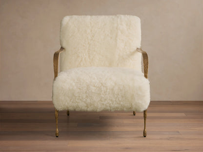 Front view of the cream Gwen Shearling Chair with fluffy shearling upholstery, brass-finished iron armrests, and sculpted legs.
