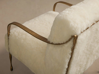 Close-up of the fluffy cream shearling upholstery and hand-hammered brass-finish iron frame of the Gwen Shearling Chair.