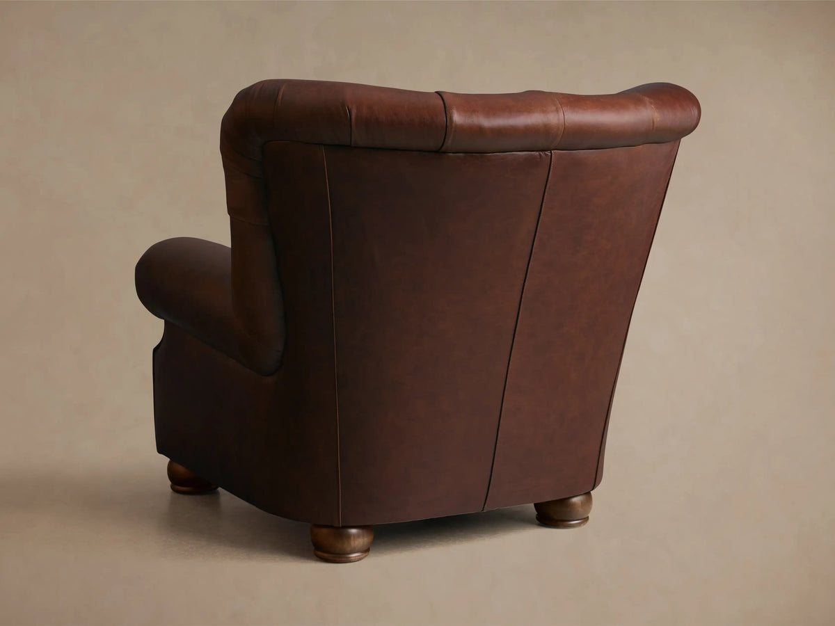 Front view of a brown tufted leather armchair with rolled arms and a single seat cushion.