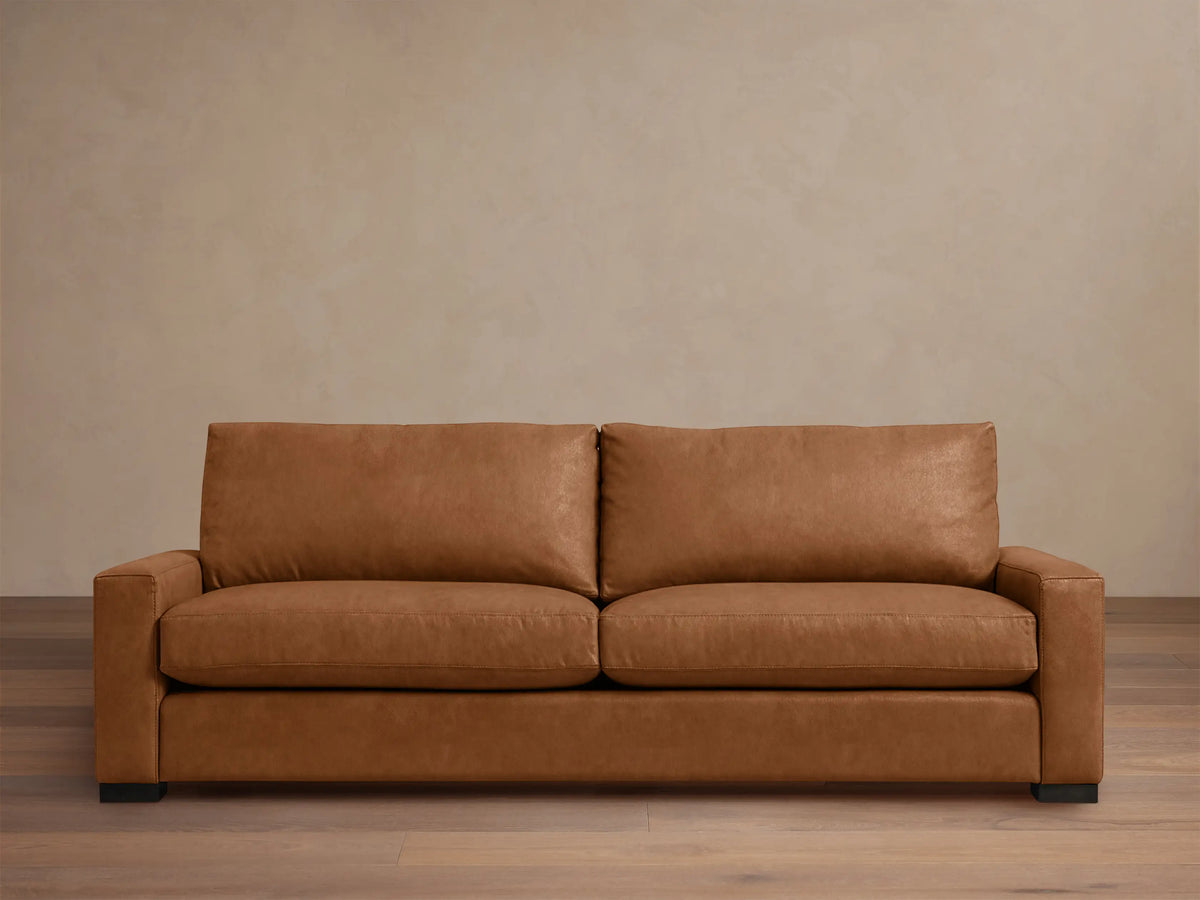 Remington Leather Sofa, medium brown, with two back and two seat cushions, and block arms, centered on a wood floor.