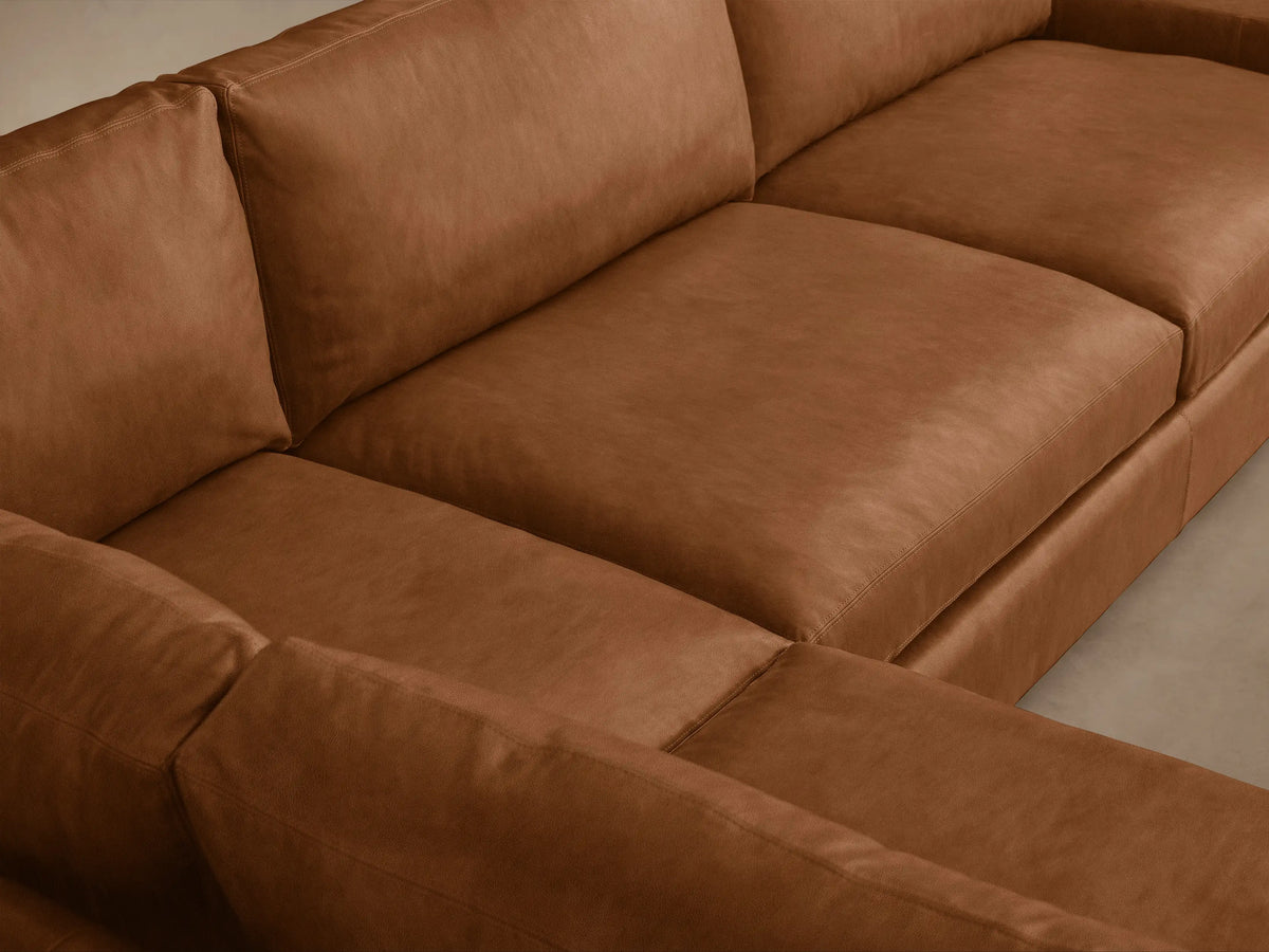 Remington L-shaped two-piece sectional in rich brown leather, featuring plush cushions, shown angled on a light wood floor.