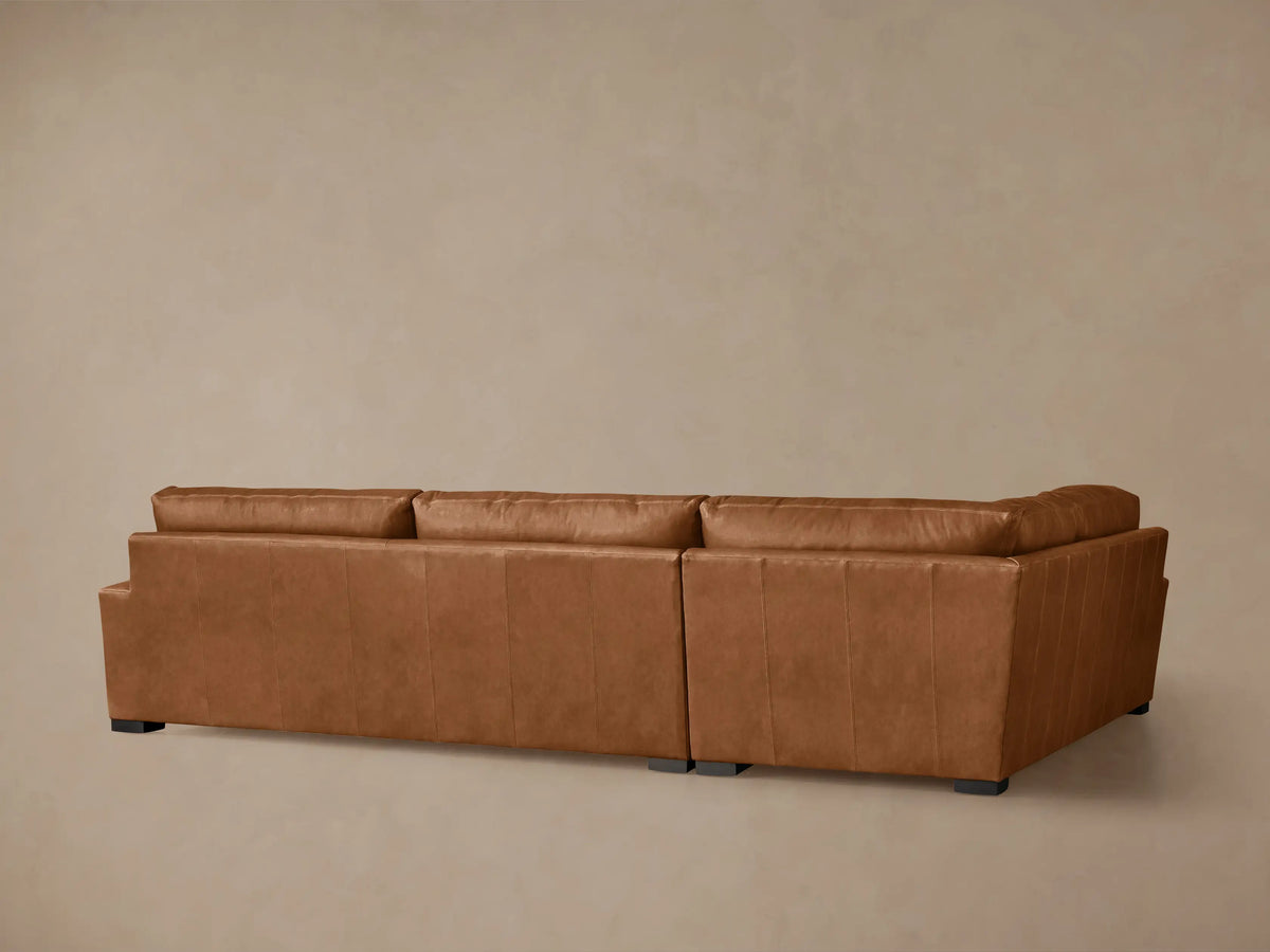 Angled close-up of a warm brown Remington Leather Two-Piece Sectional, highlighting its soft, inviting seat and back cushions.