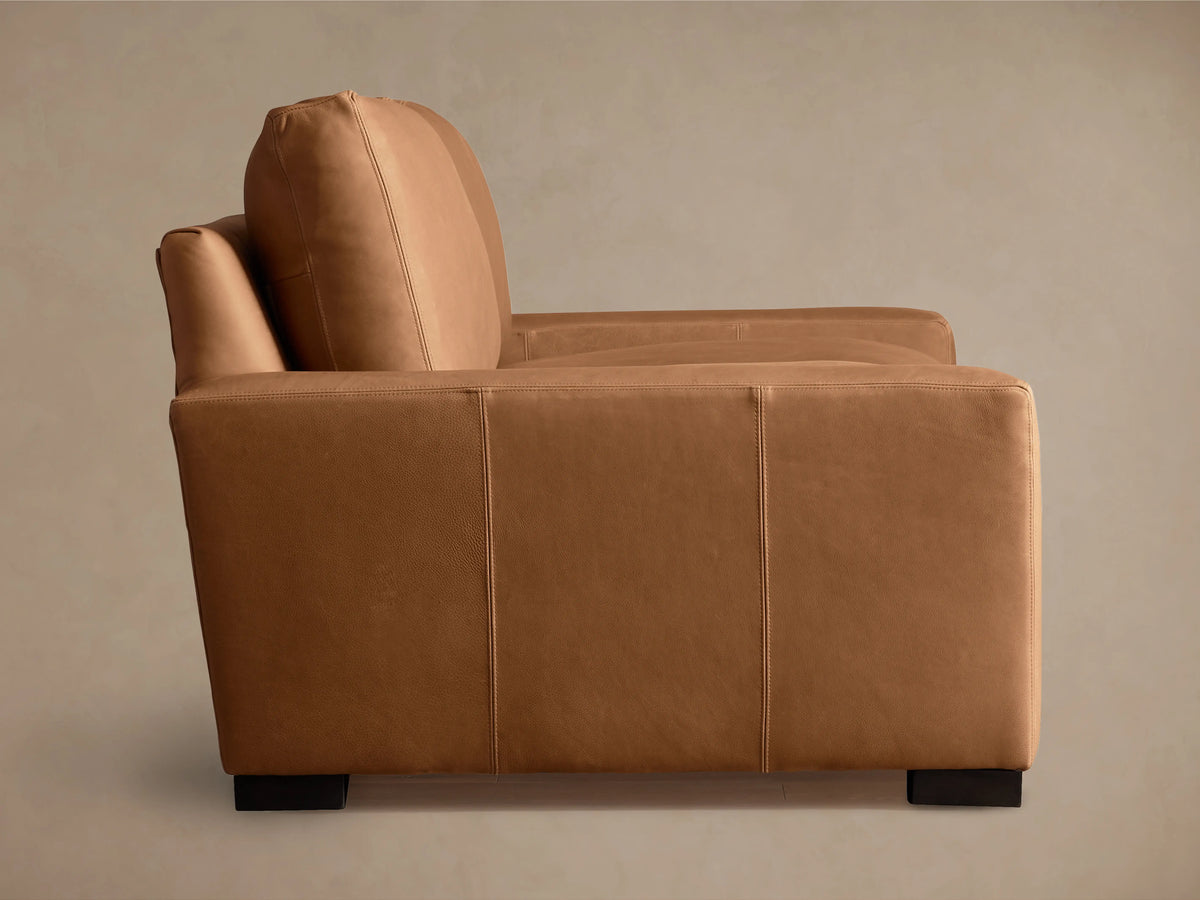 Remington Leather Sofa in light brown, featuring plush backrest and seat cushions, with sleek armrests and visible stitching details.