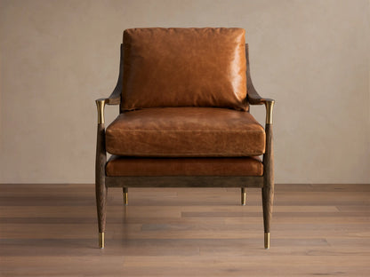 Front view of the brown leather Fisher Leather Chair. Dark wood frame with brass accents on armrests and tapered legs.