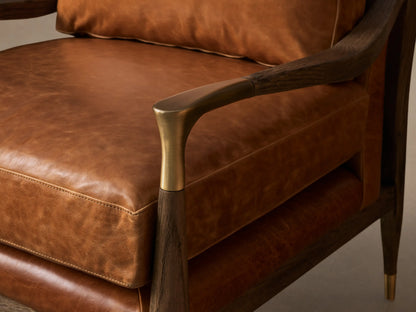 Front view of the brown leather Fisher Leather Chair, featuring a dark oak wood frame with curved armrests and brass accents.