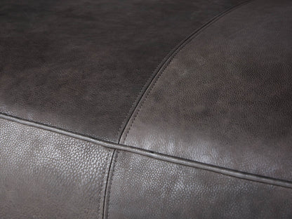 Madrone Leather Sofa, dark grey distressed, modern low-profile design with wide arms & visible white stitching, on wood floor.