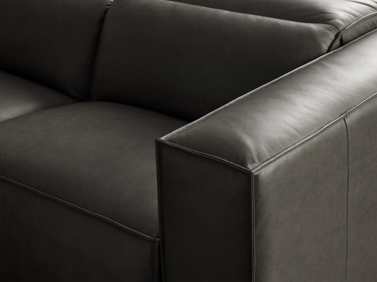 Dark gray Coburn Leather Two-Piece Motion Sofa with square arms and visible piping, on a wooden floor.