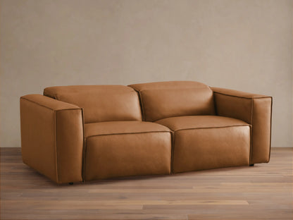 Coburn Leather Two-Piece Motion Sofa in a rich brown tone, featuring wide armrests and a minimalist design on a wooden floor.