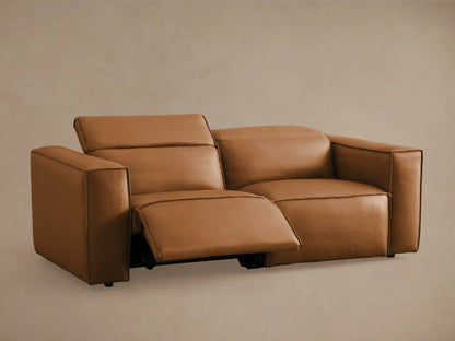 Coburn Leather Two-Piece Motion Sofa in tan leather with thick padded arms, dual backrests, and visible recline seams on beige background.
