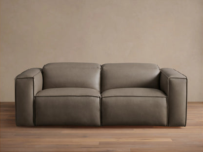 Coburn Leather Two-Piece Motion Sofa in rich brown leather with smooth, boxy arms, plush cushions, and reclining sections on a wood floor.
