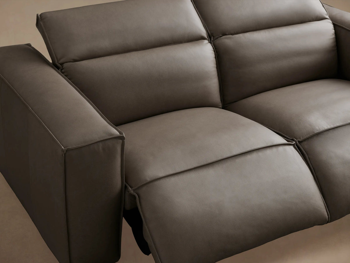 Coburn Leather Two-Piece Motion Sofa in gray leather with thick arms, two reclining seats, on hardwood floor against beige wall.